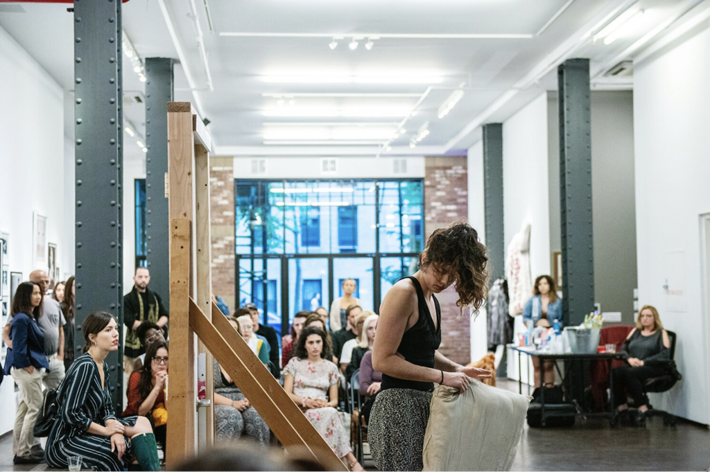 Photo: Courtesy of the Artist A woman hold a pillow in front of a crowd.